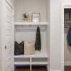 view of closet and mirror with place to sit and hang coat