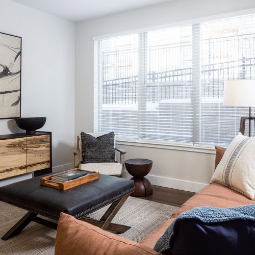 furnished apartment with couch and coffee table viewing art piece and window furnished apartment with couch and coffee table viewing art piece and window